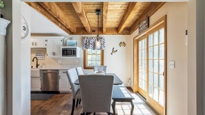 A modern kitchen with white cabinets, a stainless steel dishwasher, and a wooden ceiling.
