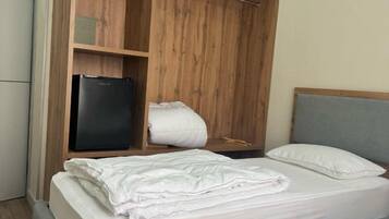 A bedroom with a bed, a wardrobe, and a small black refrigerator.