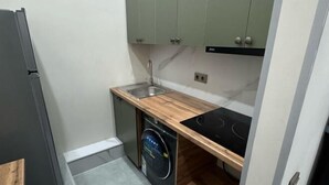 A compact kitchen with a built-in dishwasher, a sink, and a stove. - Gul Dala apartments (Almaty)
