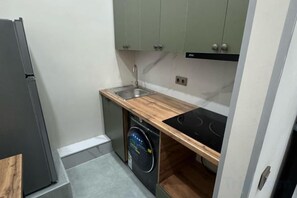 A compact kitchen with a dishwasher, a sink, and a stove. - Gul Dala apartments (Almaty)