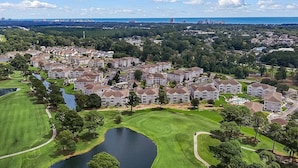 A golf course with a pond, surrounded by residential buildings.