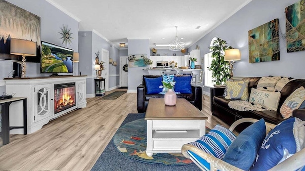 A modern living room with a fireplace, a dining area, and a kitchen.
