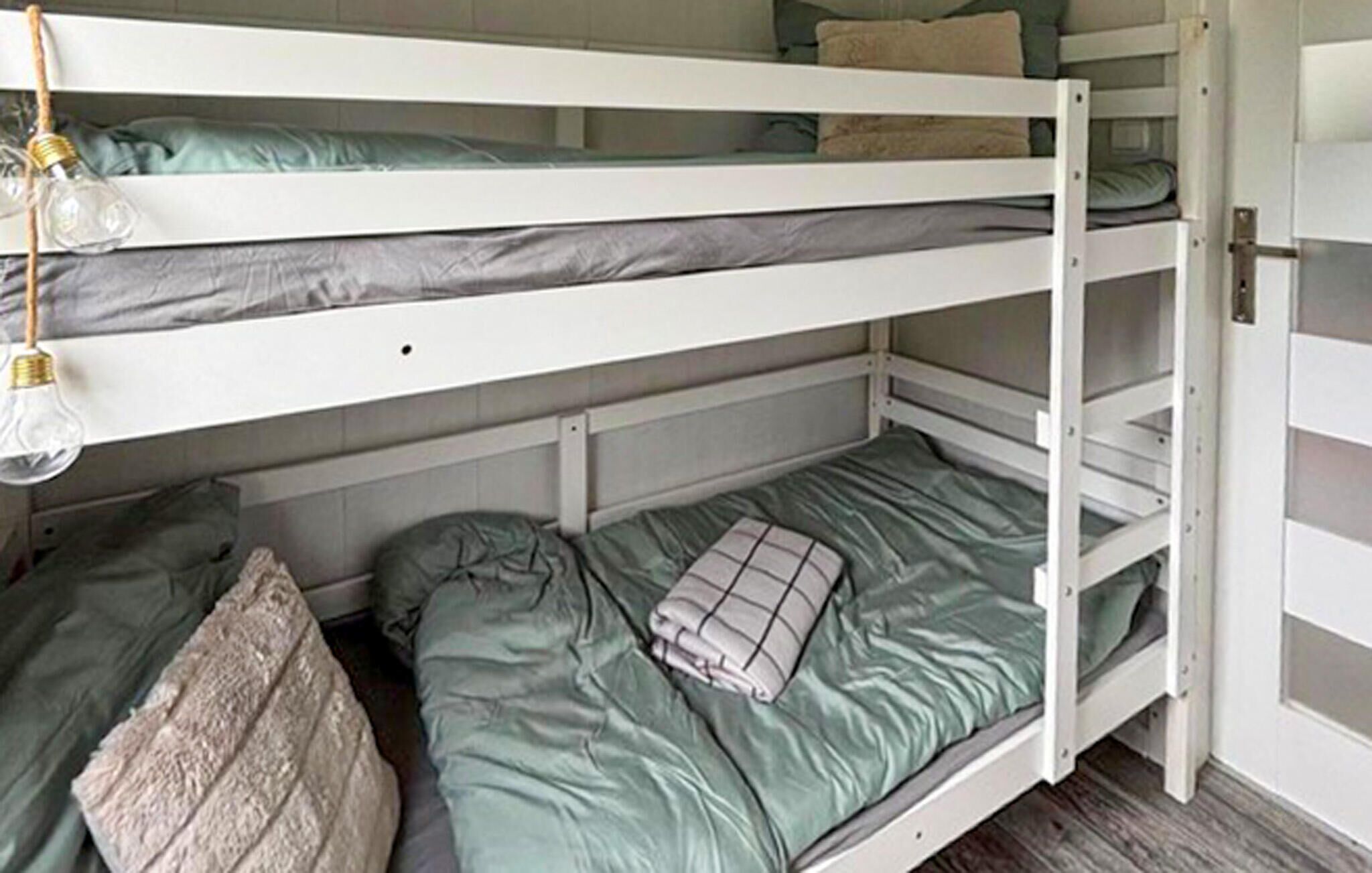 Un lit superposé à deux niveaux, chaque niveau étant équipé d’un oreiller et d’une couverture.