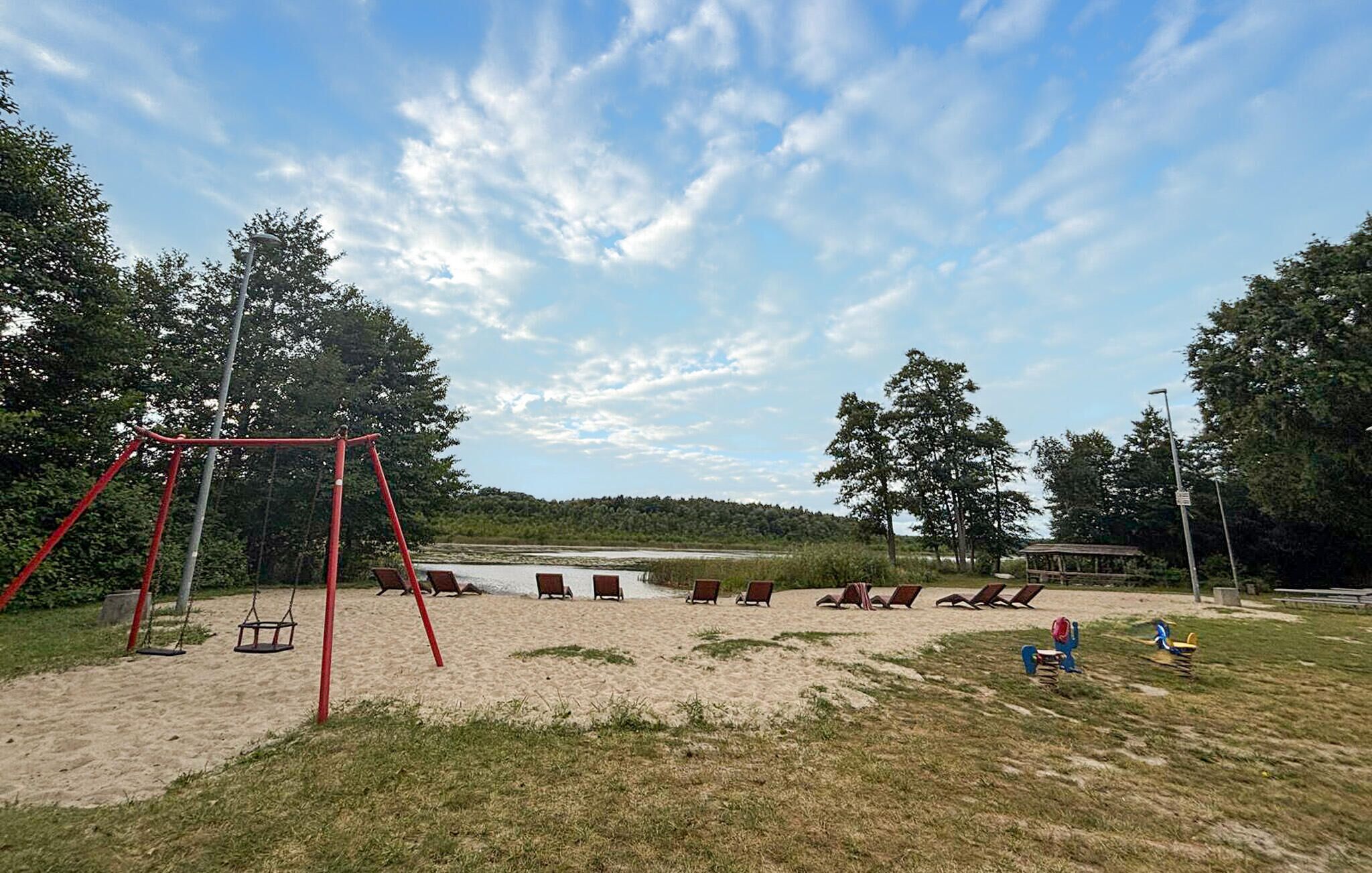 Une plage de sable avec une balançoire, des chaises longues et une table de pique-nique.
