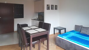Un espace de vie compact comprenant une table à manger, un canapé, un petit coin cuisine et un lit.