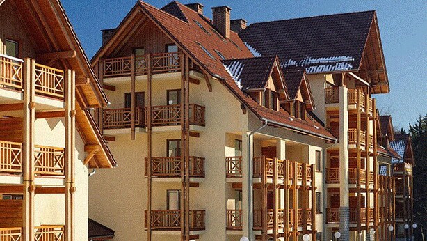 Une rangée de bâtiments en bois dotés de balcons, qui font probablement partie d’une station de ski.