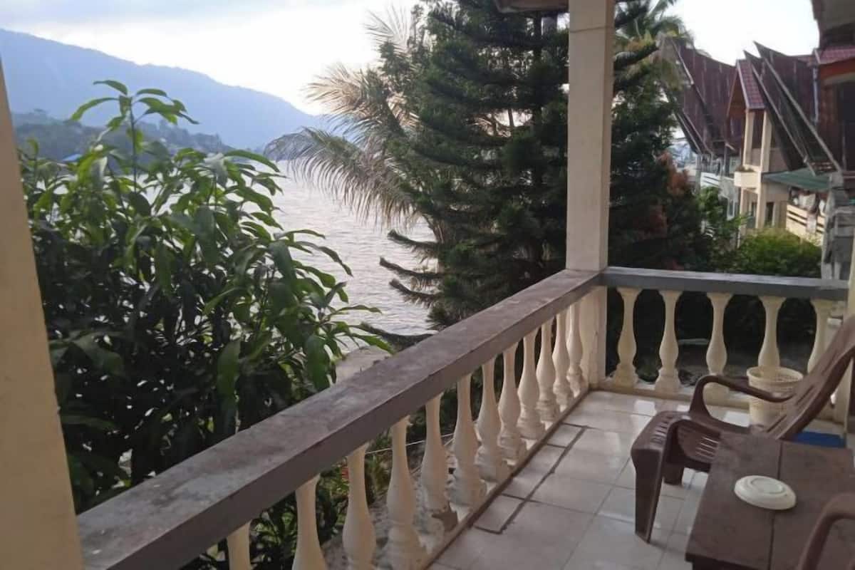 A balcony with a view of a body of water and mountains, accompanied by a table and chairs.