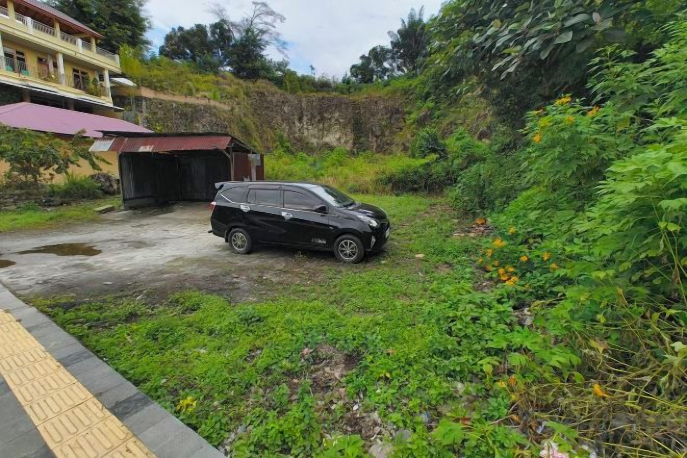 A black SUV parked on a grassy area with a building in the background.