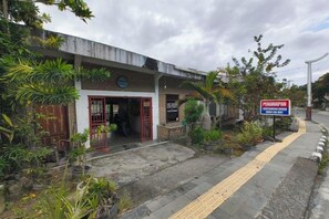 A building with a gated entrance, a signboard, and potted plants. - Sibayak Guest house (Samosir Regency)