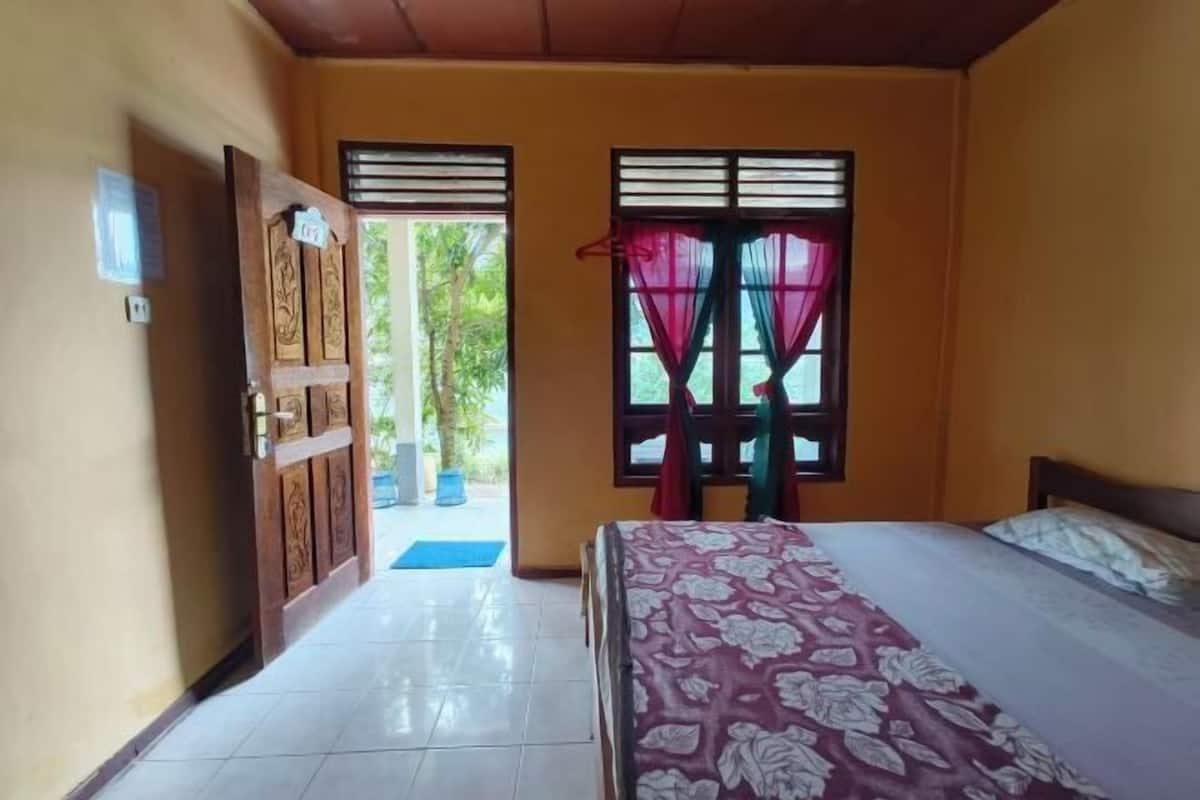 A room with a bed, a door, and a window with curtains.