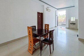 Un comedor con una mesa y sillas de madera, una puerta y vista al exterior.