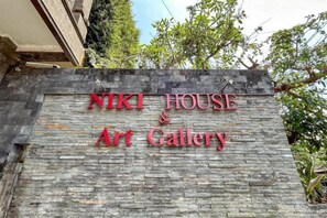 Una pared de piedra con el texto 'NIKI HOUSE & Art Gallery' en letras rojas.