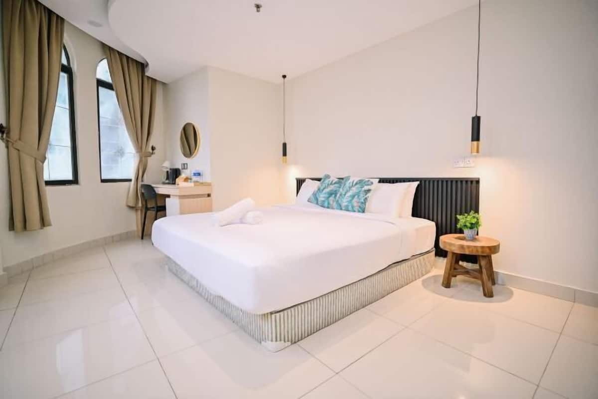 A modern hotel room with a large bed, a desk, and a small stool.