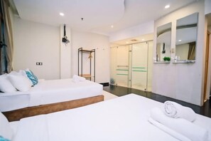 Habitación de hotel con dos camas, un espejo grande y una puerta corredera que da a un baño.