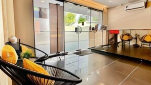 A modern hotel lobby with a glass partition, black chairs with yellow cushions, and a dining area with round tables and chairs. - Swing & Pillows @ Central Market Kuala Lumpur (Kuala Lumpur)