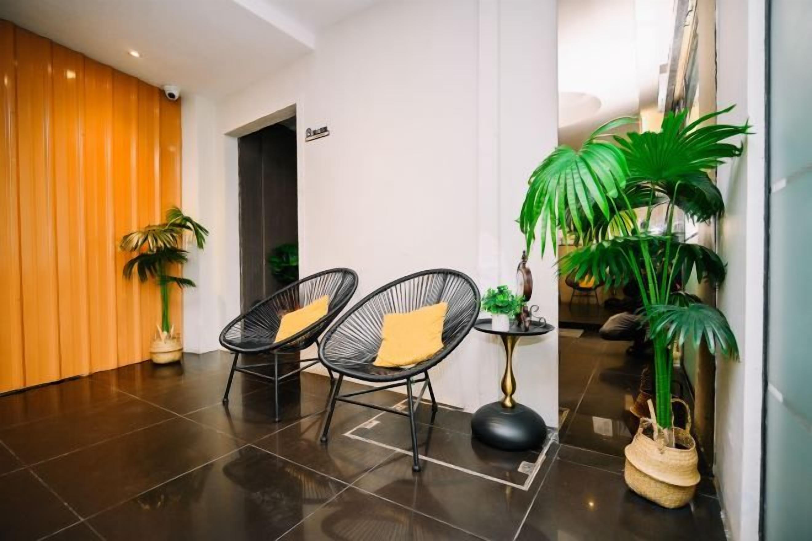 Un vestíbulo con dos sillones de mimbre negro, una mesita redonda y una planta en maceta.