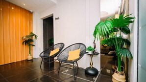 A lobby with two black wire-framed chairs with yellow cushions, a small round table with a plant, and a large potted plant. - Swing & Pillows @ Central Market Kuala Lumpur (Kuala Lumpur)