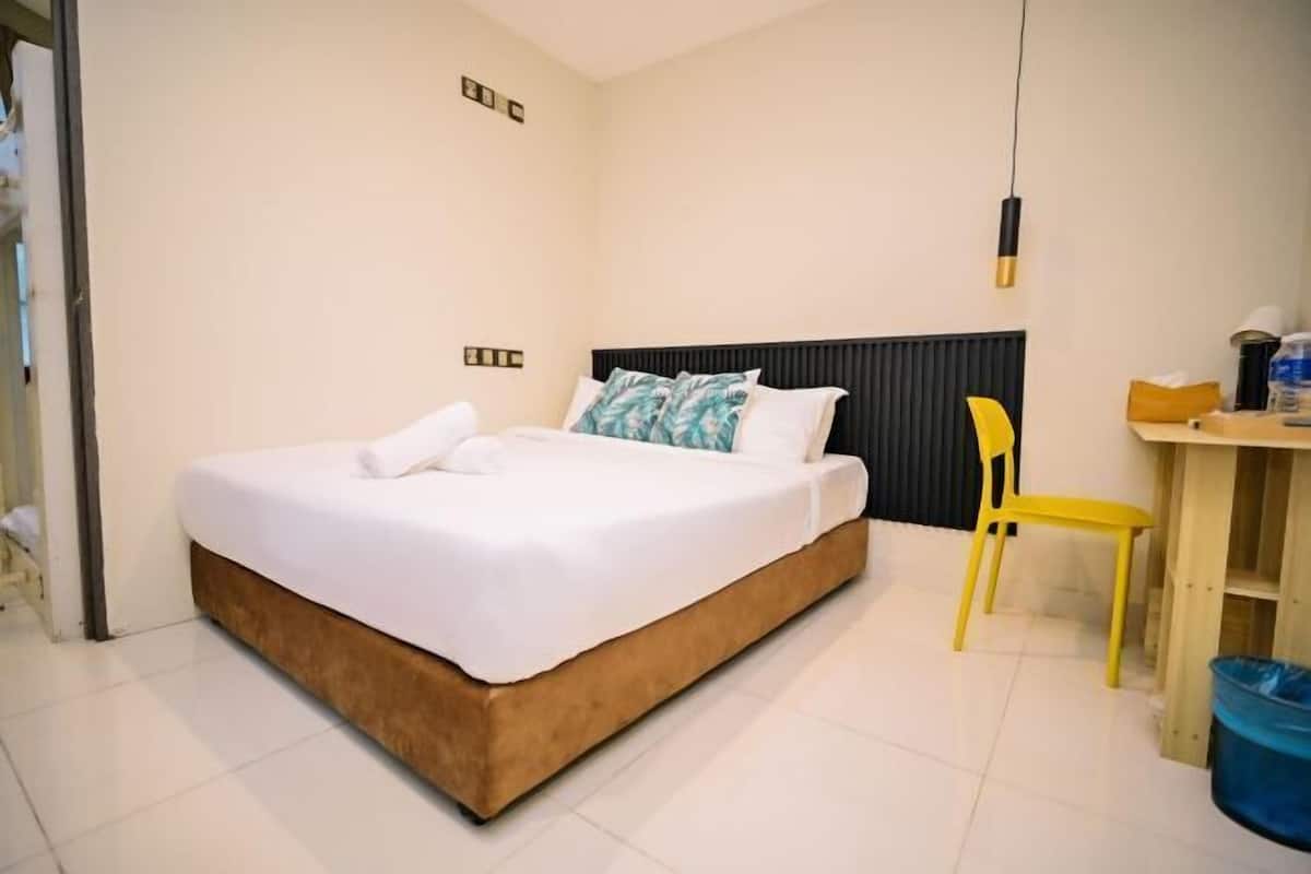 A bedroom with a bed, a desk, and a chair.