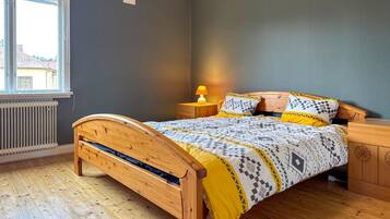 Un dormitorio con una cama de madera, una mesita de noche con una lámpara y un radiador.