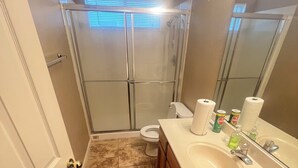 A bathroom with a shower, toilet, sink, and a mirror. - House with AC in Elk Grove (Elk Grove)