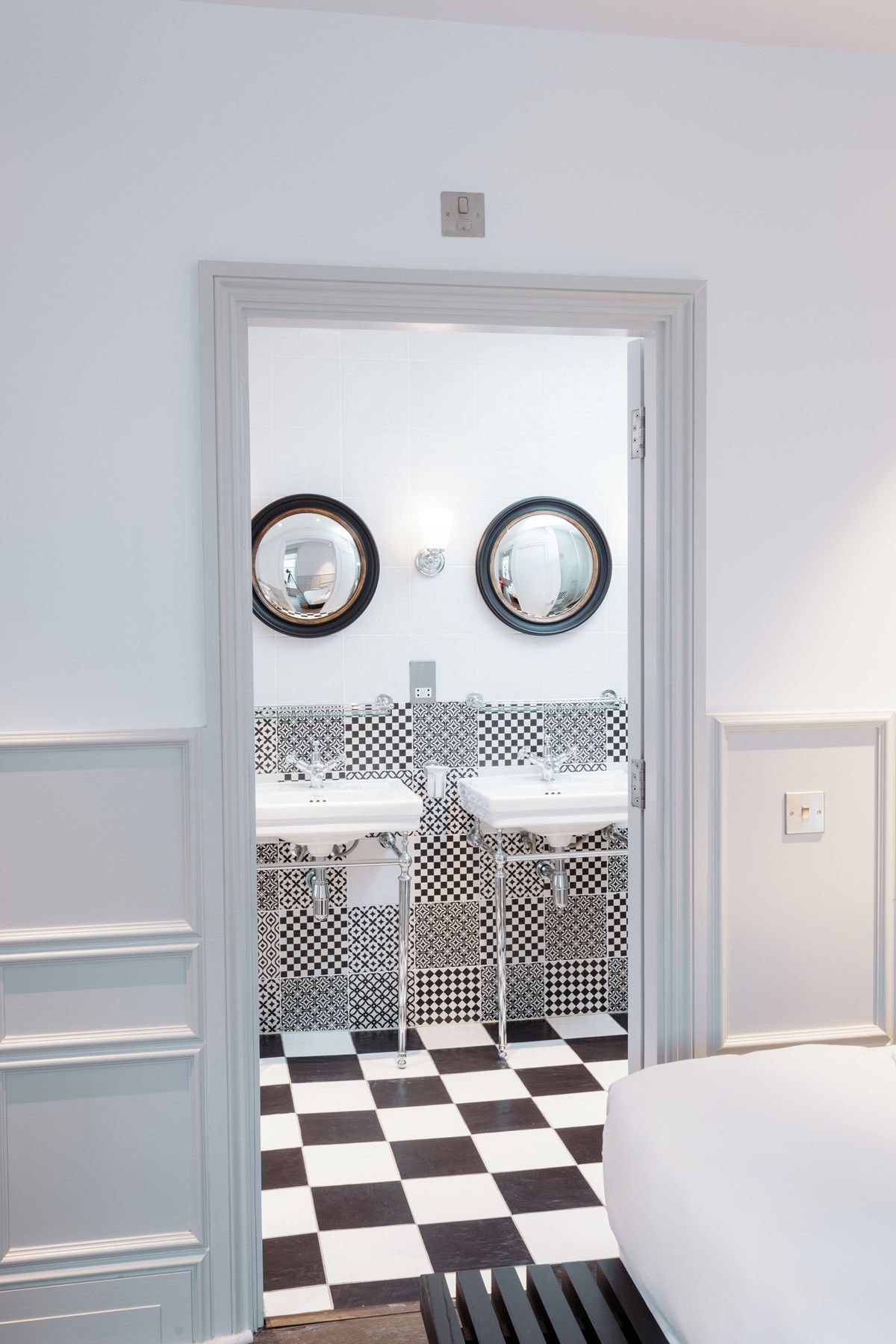 A bathroom with two sinks, a checkered floor, and a mirror with a circular frame.