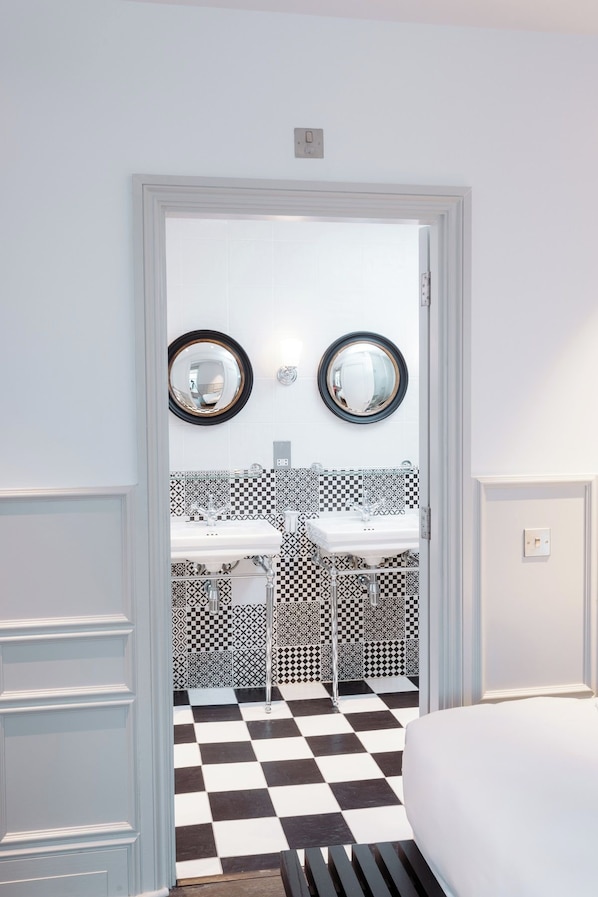 Un baño con dos lavamanos, piso de tablones y un espejo con marco circular.