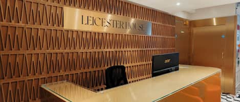 Una recepción con un panel de madera y un letrero que dice "LEICESTER HOUSE".