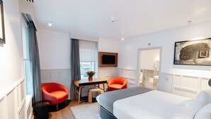 A modern hotel room with a large bed, a desk with a chair, a television, and a painting on the wall. - Leicester House Hotel (London)