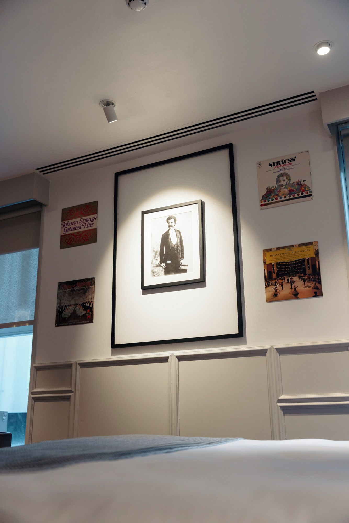 A framed portrait on a wall, surrounded by various posters and framed pictures.