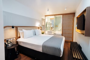 A modern hotel room with a large bed, bedside table, lamp, and a TV mounted on the wall. - Leicester House Hotel (London)