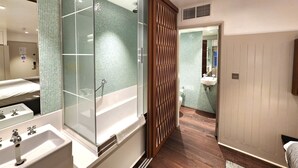 A modern bathroom with a large mirror, a glass-enclosed shower, and a wooden partition. - Leicester House Hotel (London)