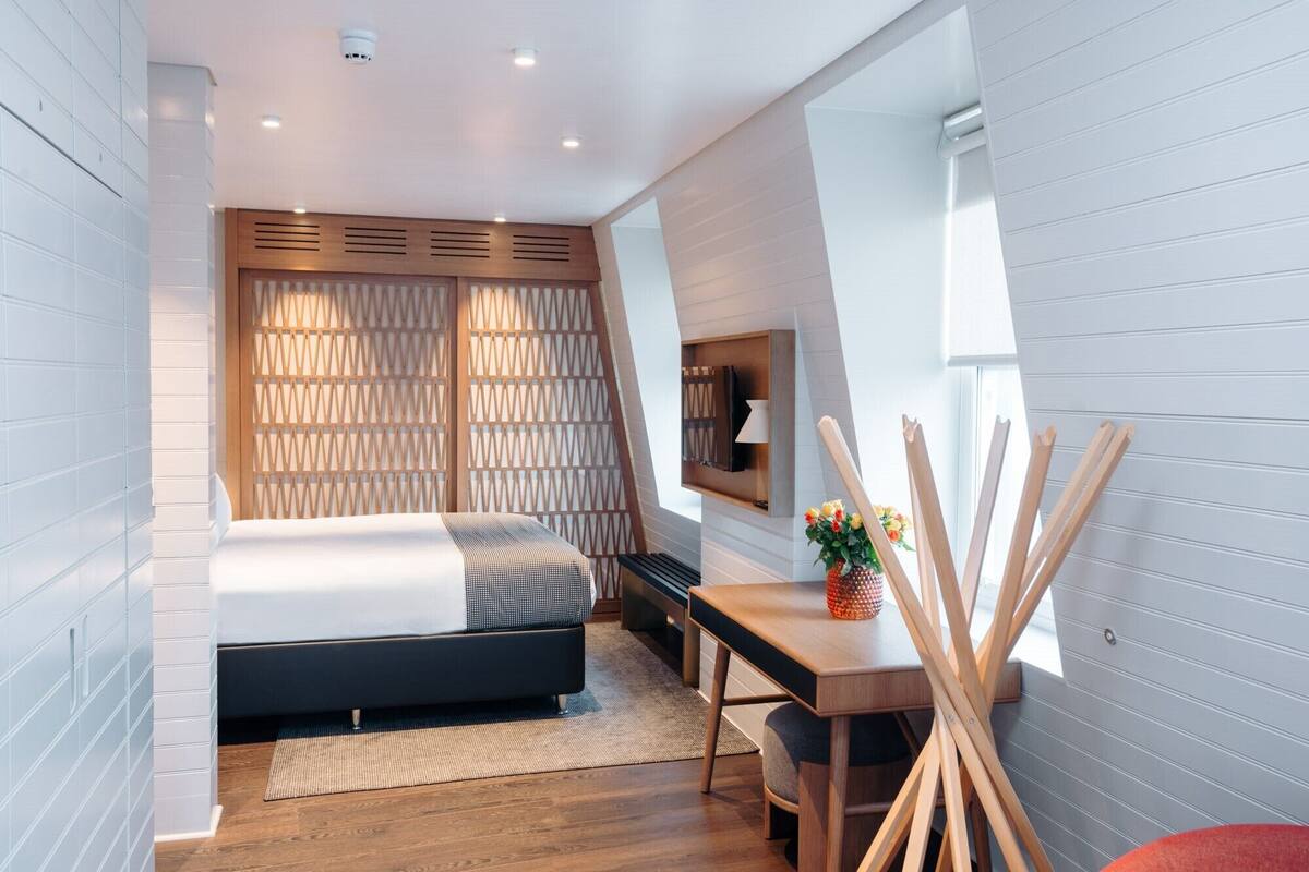 A modern bedroom with a bed, bedside table, and a small desk area.