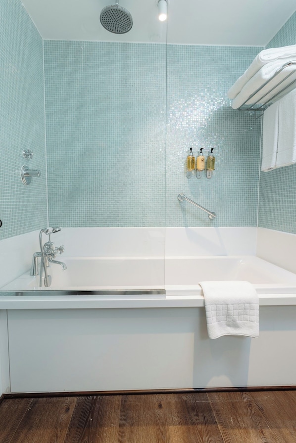A modern bathroom with a freestanding bathtub, a showerhead, and two bottles of liquid soap. - Leicester House Hotel (London)