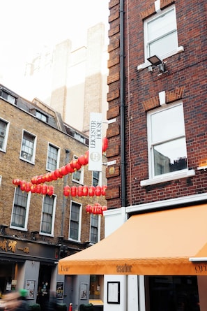 A brick building with a sign for "Leicester House" and a row of red lanterns. - Leicester House Hotel (London)