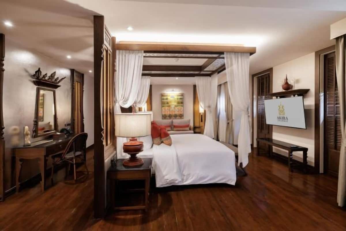 Una habitación de hotel con cama, escritorio, silla, lámpara y un cuadro en la pared.