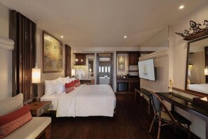 Ein Hotelzimmer mit Bett, Schreibtisch, Sessel, Fernseher und einem großen Spiegel.