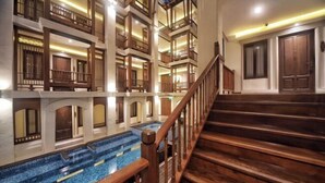 Een meerlaags hotel met een centraal gelegen zwembad, houten balkons en een trap.