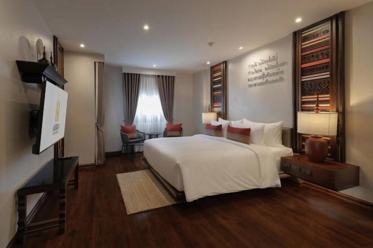 Habitación de hotel con una cama grande, un escritorio, una silla, un televisor y un adornado en la pared.