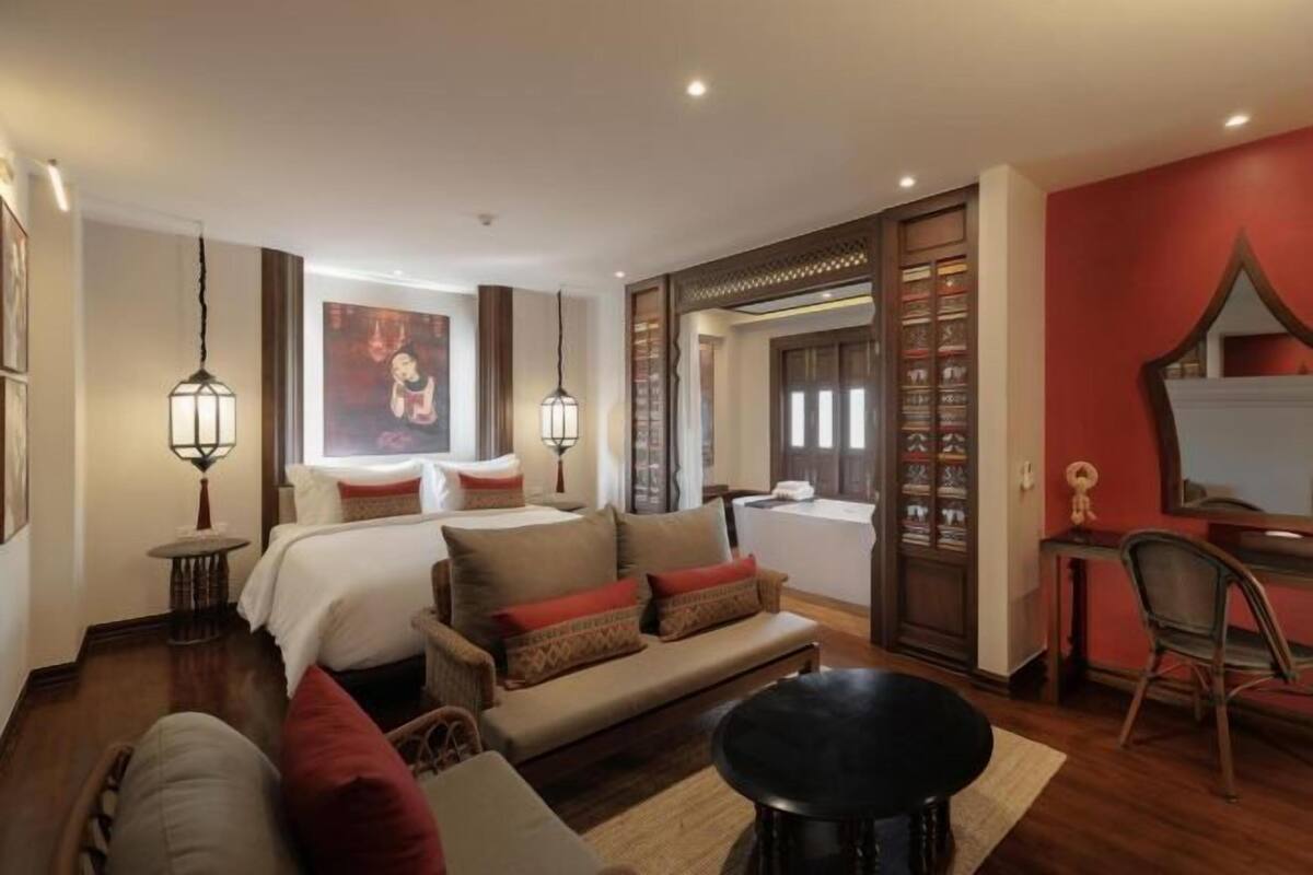 Habitación de hotel con cama, sofá, escritorio y una ventana grande.