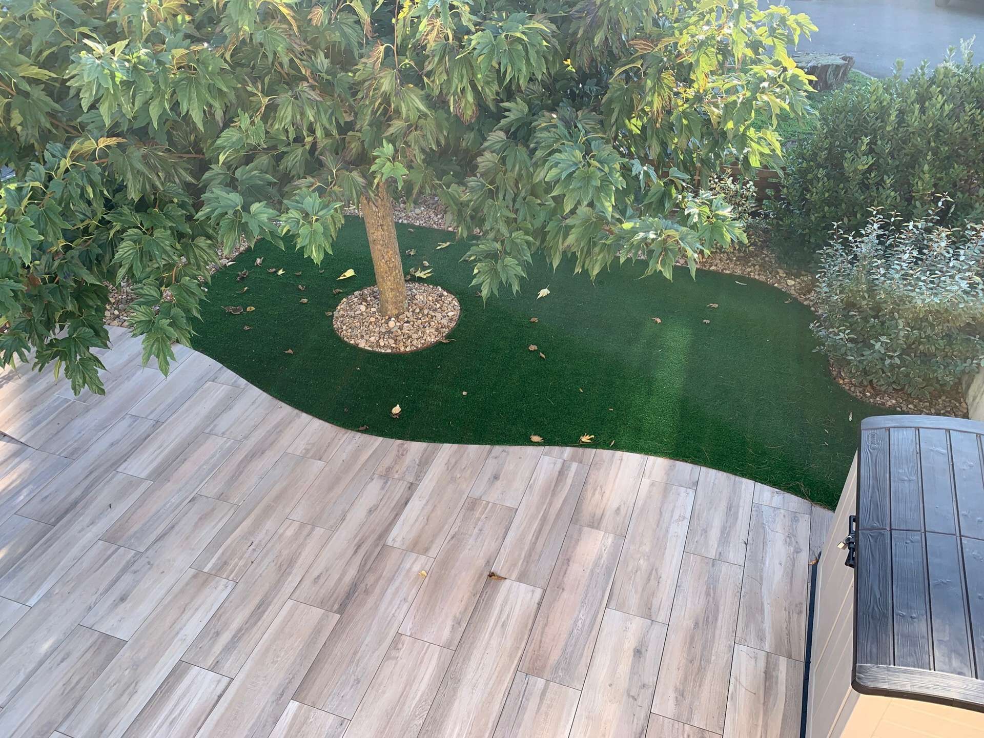 A wooden deck with a tree and green artificial turf.
