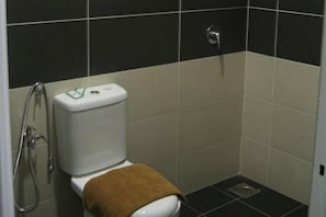 A bathroom with a toilet, a shower, and a sink.