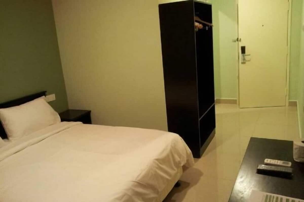 Habitación de hotel con cama, armario, mesita de noche y mesa de centro con un control remoto.