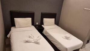 Habitación de hotel con dos camas individuales, cada una con una almohada y una toalla.