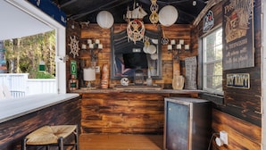 Un bar à thème maritime, avec des murs en bois, un petit réfrigérateur et un comptoir avec des tabourets.