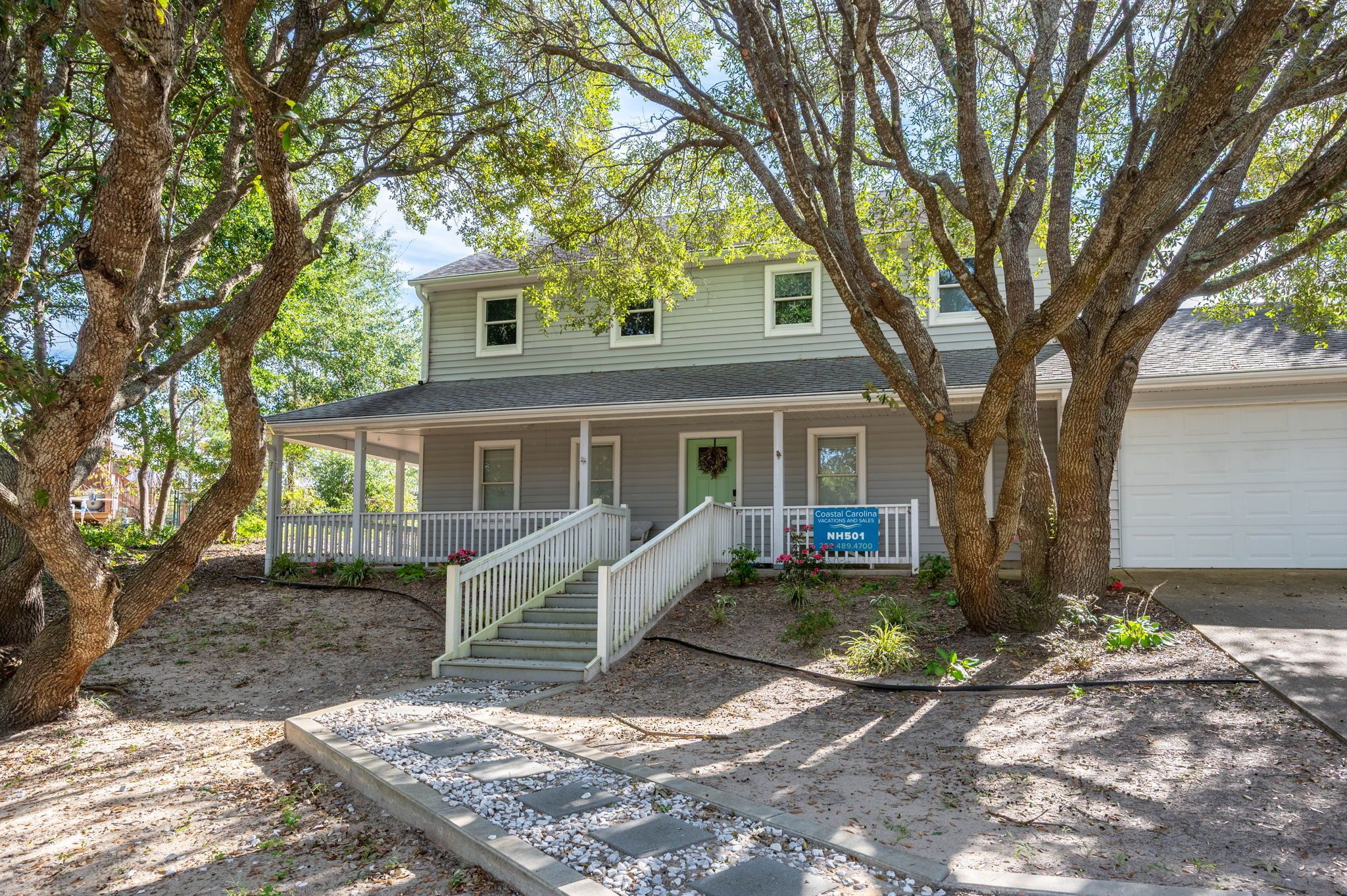 A two-story house with a covered porch and a front staircase.