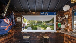 Un coin bar rustique avec une grande fenêtre donnant sur un jardin, des murs en bois et une enseigne indiquant « Rugby Rd. ».