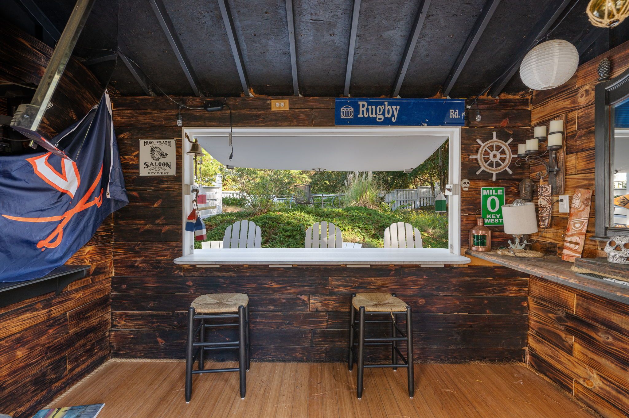 Angolo bar rustico con un'ampia finestra vista giardino, pareti in legno e un cartello che indica 'Rugby Rd'.