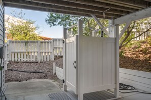 A covered outdoor area with a white gate, a concrete path, and a wooden fence in the background.
