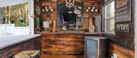 Eine schiffslastige Bar mit Holzwänden, einem kleinen Kühlschrank und einer Theke mit Hockern.