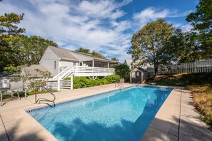 A swimming pool with a covered deck area, a small shed, and a fenced yard.